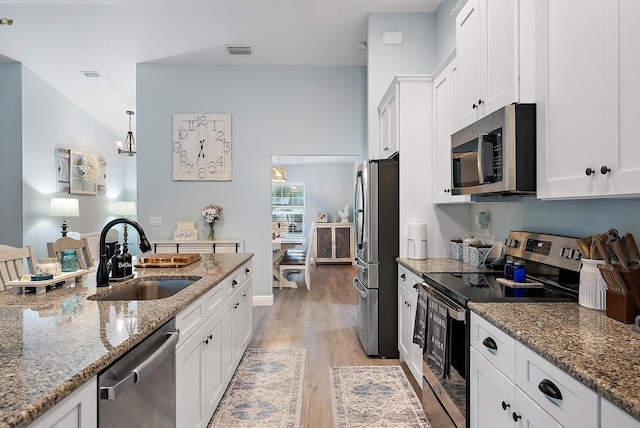 kitchen featuring stone counters, stainless steel appliances, sink, and white cabinets