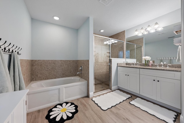 bathroom with vanity, hardwood / wood-style flooring, plus walk in shower, and a textured ceiling