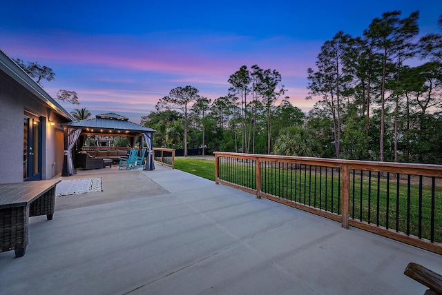 patio terrace at dusk with a gazebo, an outdoor hangout area, and a lawn