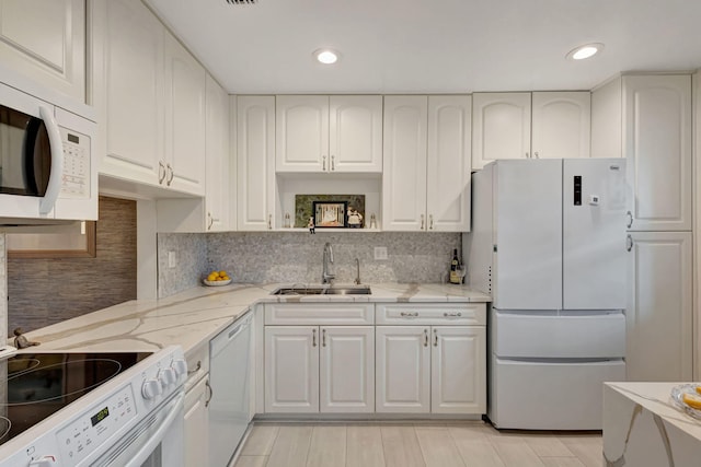 kitchen with a sink, white appliances, and white cabinets