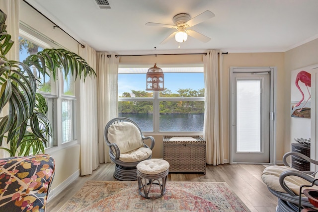 sitting room with visible vents, a water view, light wood finished floors, and ceiling fan