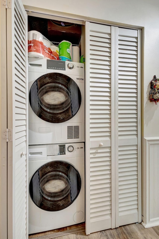 laundry area with laundry area, wood finished floors, and stacked washer / drying machine