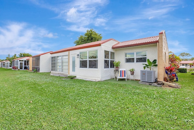 rear view of house with stucco siding, a tiled roof, and a lawn