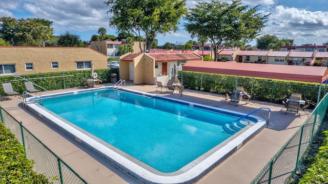 community pool with a patio and fence