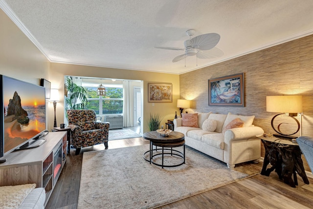 living room with a textured ceiling, crown molding, ceiling fan, and wood finished floors