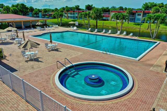 pool with a patio area, a hot tub, and fence