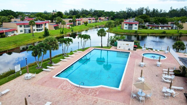 community pool featuring a patio area, a water view, and fence