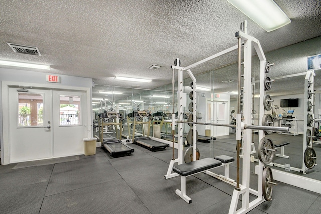 workout area featuring french doors, visible vents, and a textured ceiling