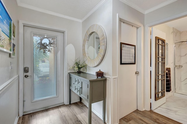 foyer entrance featuring light wood-style flooring, a textured ceiling, and ornamental molding