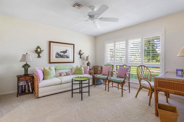 carpeted living room featuring ceiling fan and a textured ceiling