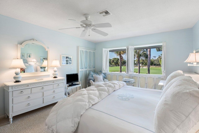 carpeted bedroom featuring ceiling fan, a closet, and a textured ceiling