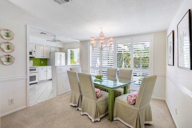 dining room featuring ceiling fan with notable chandelier, light colored carpet, and a textured ceiling