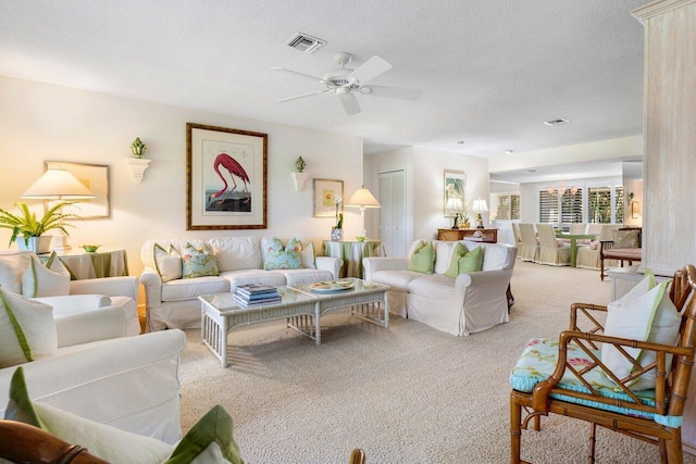 carpeted living room with ceiling fan and a textured ceiling