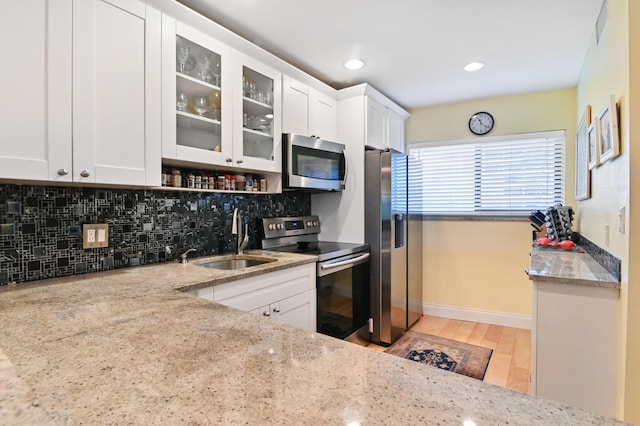 kitchen featuring stainless steel appliances, sink, white cabinets, and light stone counters