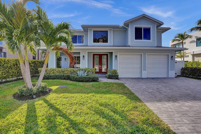 view of front of property with a garage, a front yard, french doors, and decorative driveway