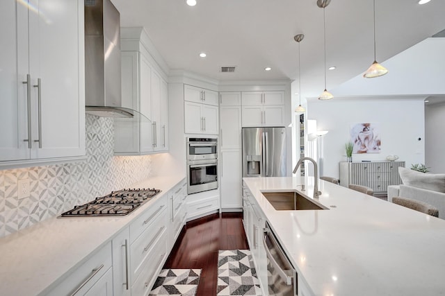 kitchen with sink, decorative light fixtures, white cabinets, and wall chimney exhaust hood