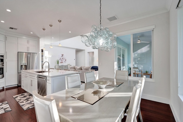 dining area with ornamental molding, sink, ceiling fan with notable chandelier, and dark hardwood / wood-style floors