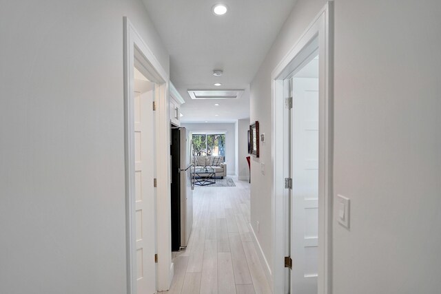 kitchen with sink, appliances with stainless steel finishes, light stone countertops, light hardwood / wood-style floors, and white cabinets