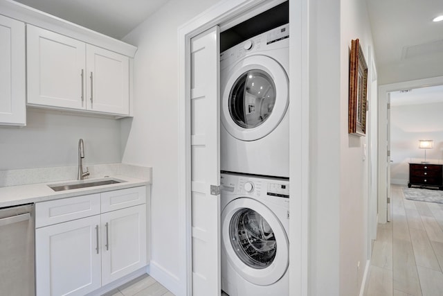 laundry room with stacked washer / drying machine, light hardwood / wood-style floors, and sink