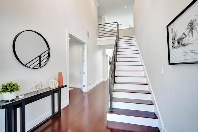 staircase featuring hardwood / wood-style flooring and a towering ceiling