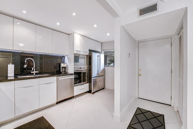 3605 S Ocean Blvd Unit 312, South Palm Beach, FL 33480 - kitchen with dark stone countertops, a sink, stainless steel appliances, white cabinets, and visible vents