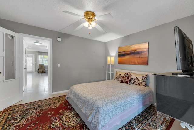 bedroom with ceiling fan, a textured ceiling, and light tile patterned flooring