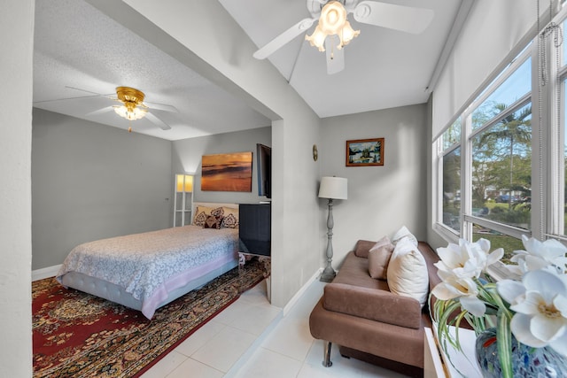 bedroom featuring ceiling fan, light tile patterned floors, and a textured ceiling