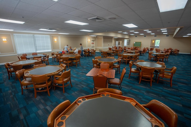 carpeted dining space with a paneled ceiling