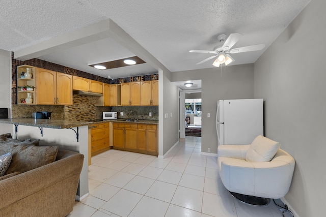 kitchen with white appliances, a textured ceiling, light tile patterned floors, ceiling fan, and decorative backsplash