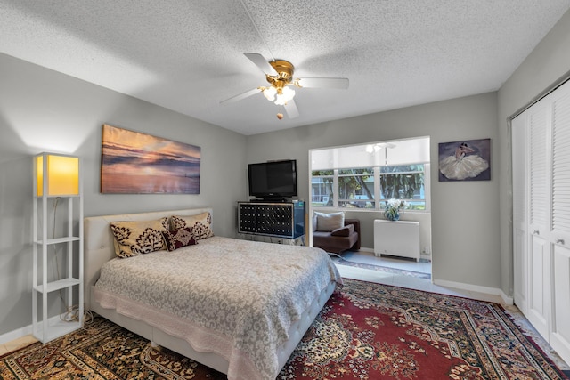 tiled bedroom featuring ceiling fan, a closet, and a textured ceiling