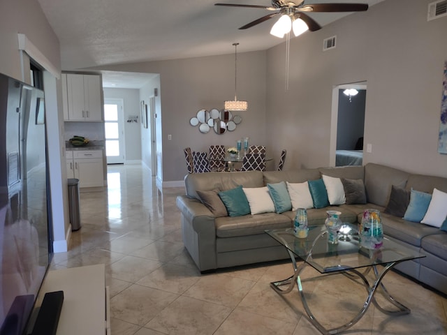 living room featuring ceiling fan with notable chandelier and vaulted ceiling