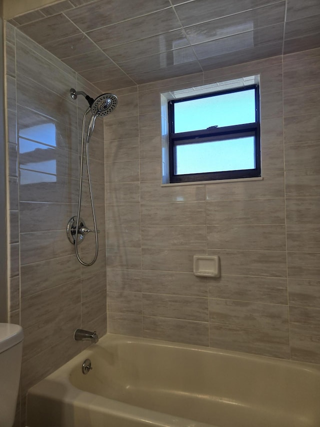 bathroom featuring tiled shower / bath and toilet