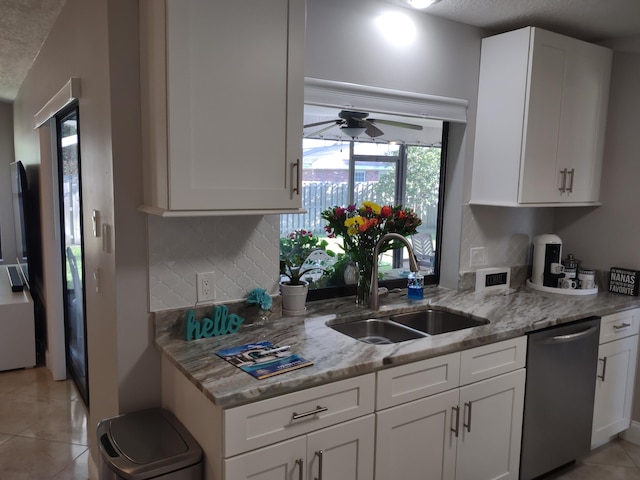 kitchen featuring light tile patterned flooring, white cabinetry, sink, stainless steel dishwasher, and light stone countertops