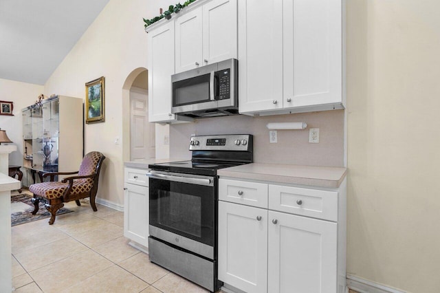 kitchen featuring white cabinetry, light tile patterned floors, stainless steel appliances, and lofted ceiling