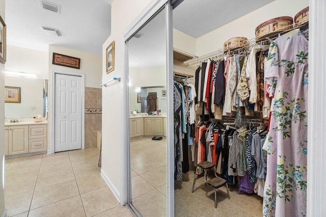 spacious closet featuring sink and light tile patterned floors