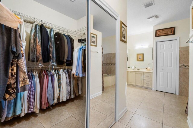 bathroom with plenty of natural light, tile patterned floors, and a tub to relax in