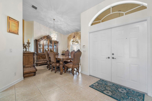 tiled entrance foyer with lofted ceiling and a chandelier