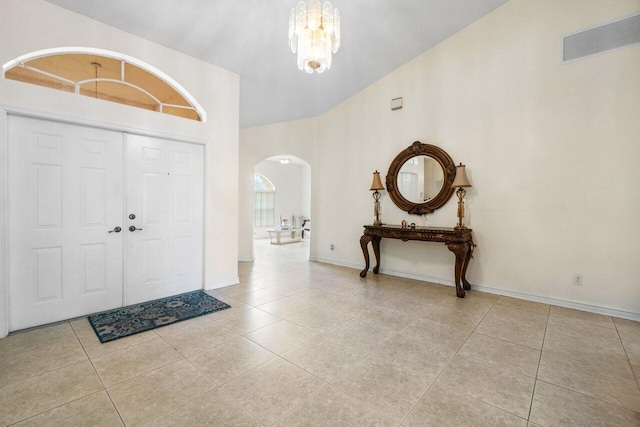 entryway featuring high vaulted ceiling, light tile patterned floors, and a chandelier