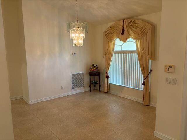 tiled entryway with a towering ceiling and a chandelier