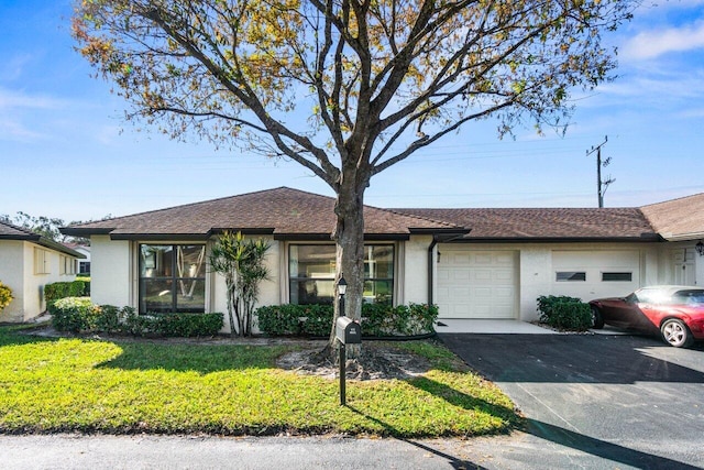 view of front of property with an attached garage, a front lawn, aphalt driveway, and stucco siding