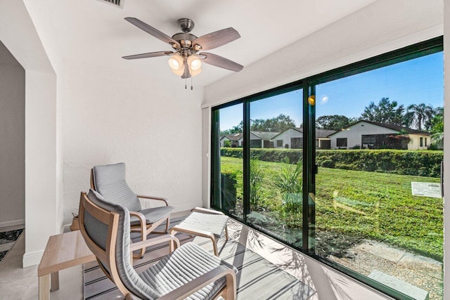 sunroom featuring a residential view and ceiling fan