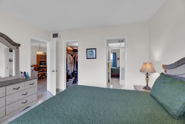 bedroom with light tile patterned floors, a walk in closet, a closet, and ensuite bathroom