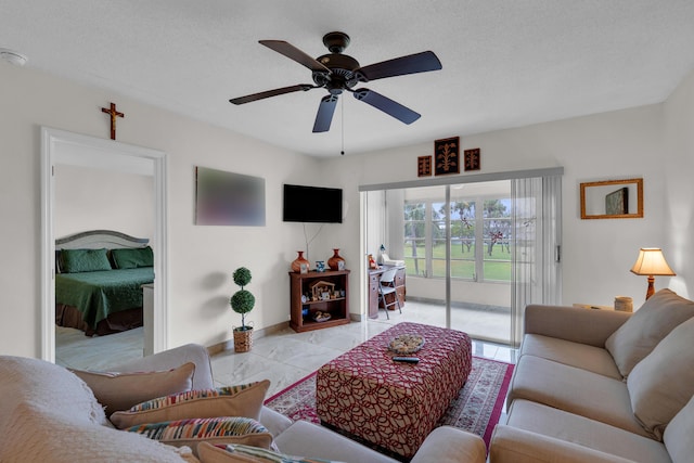 living room with ceiling fan, light tile patterned flooring, and a textured ceiling