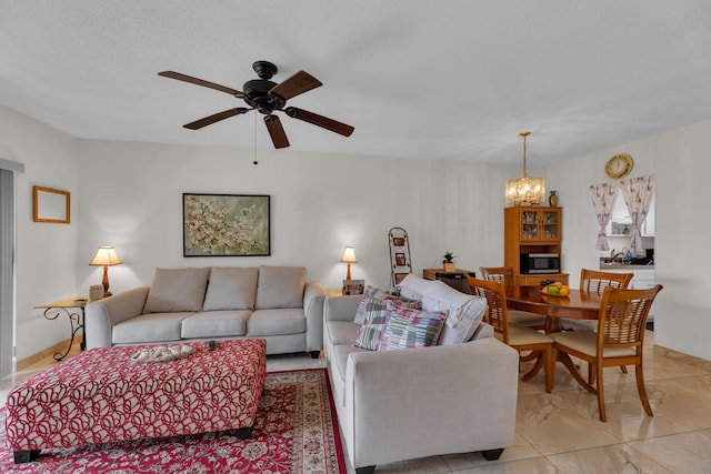 living room featuring ceiling fan with notable chandelier and a textured ceiling