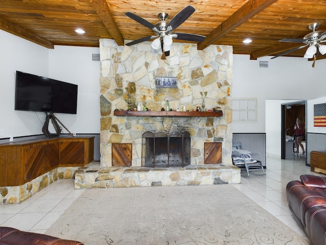 living room featuring beam ceiling, light tile patterned floors, wood ceiling, and a stone fireplace