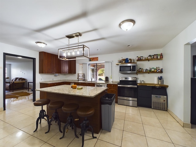 kitchen with pendant lighting, sink, light tile patterned floors, stainless steel appliances, and a center island