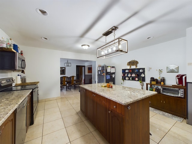 kitchen featuring pendant lighting, appliances with stainless steel finishes, a center island, and light tile patterned floors