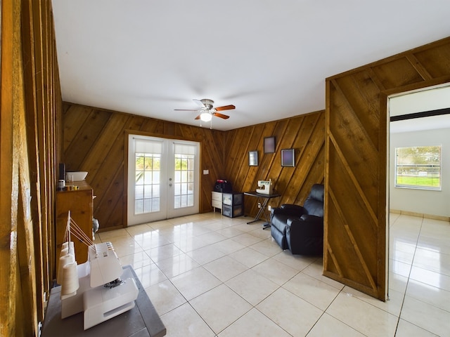 living room featuring a wealth of natural light, french doors, wooden walls, and light tile patterned flooring