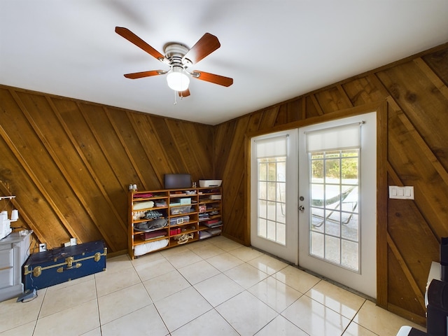 entryway featuring ceiling fan, light tile patterned floors, wooden walls, and french doors