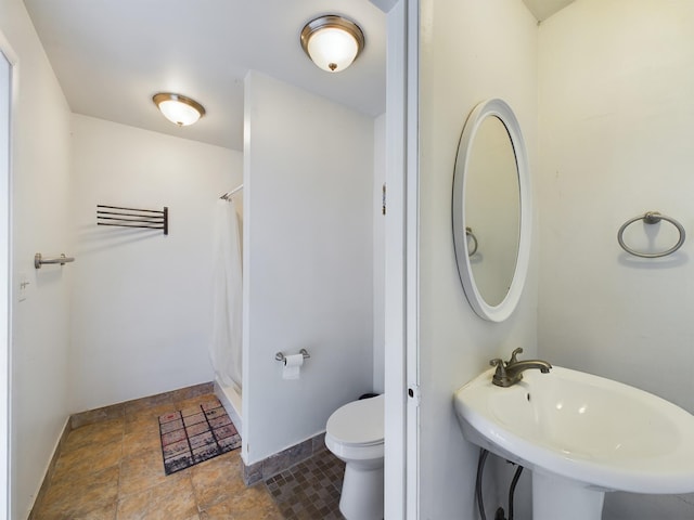 bathroom featuring sink, curtained shower, and toilet